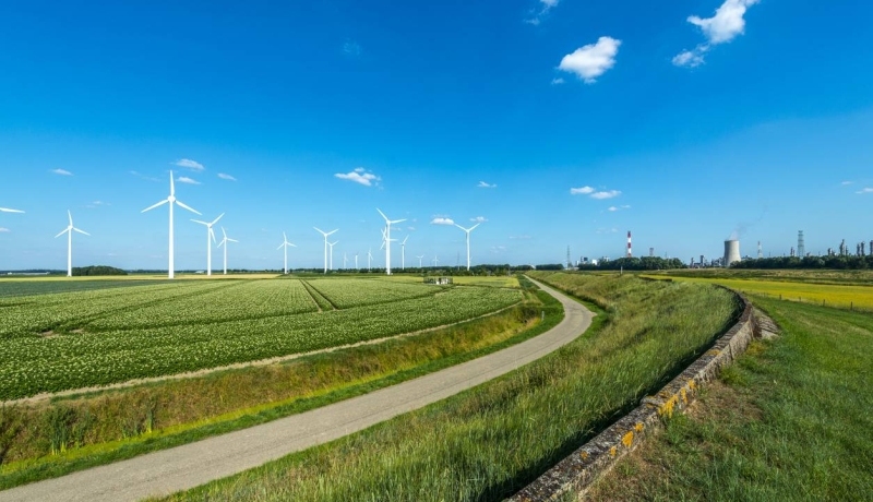 Nederlands landschap met blauwe lucht, windmolens en energiecentrale