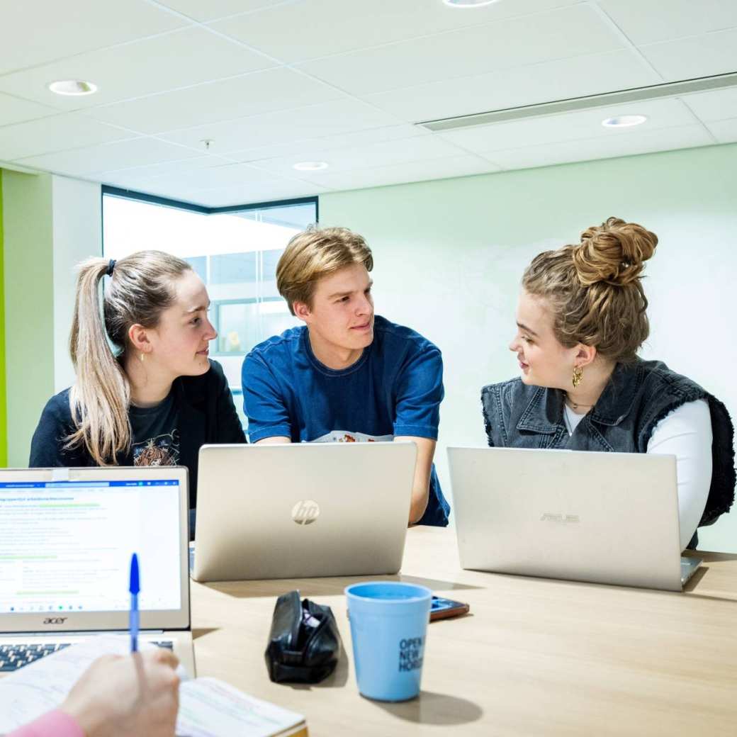 Studenten Human Resource Management (HRM) overleggen in de studio met de laptop erbij