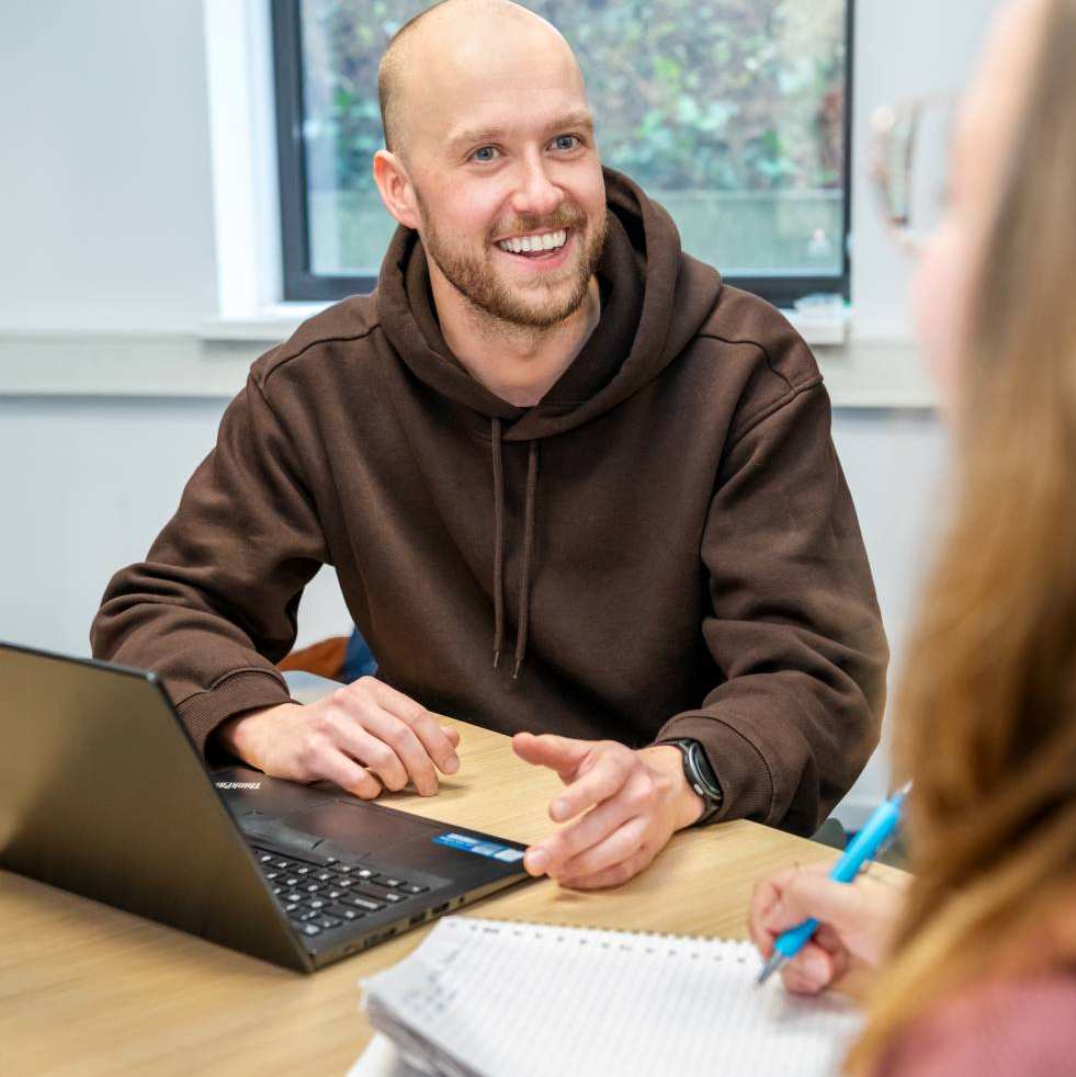 Mannelijke student lacht naar medestudenten.