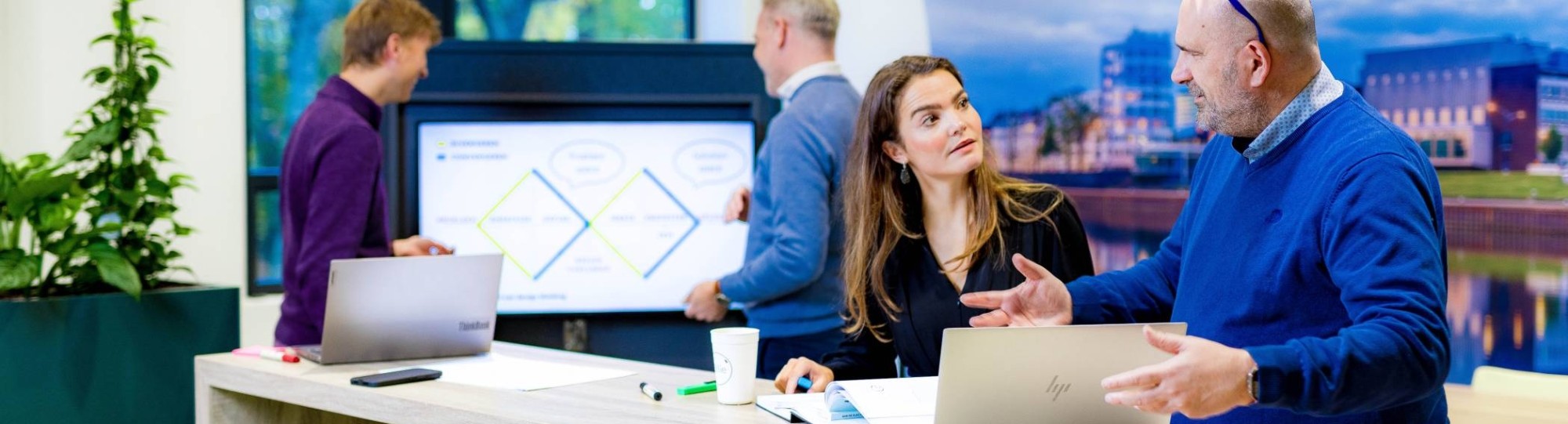 Studenten van de master Business Sales in overleg, samenwerken met laptop.