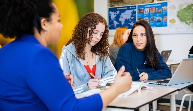 2 leerlingen krijgen uitleg aan tafel van een docenten op het Citadel College. 
