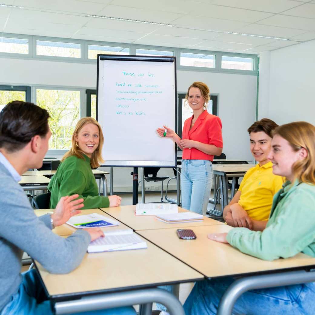 Studenten van Facility Management met een docent in de klas voor uitleg.