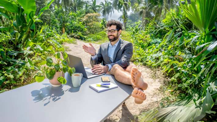 Man zit achter laptop in de jungle met zijn benen omhoog