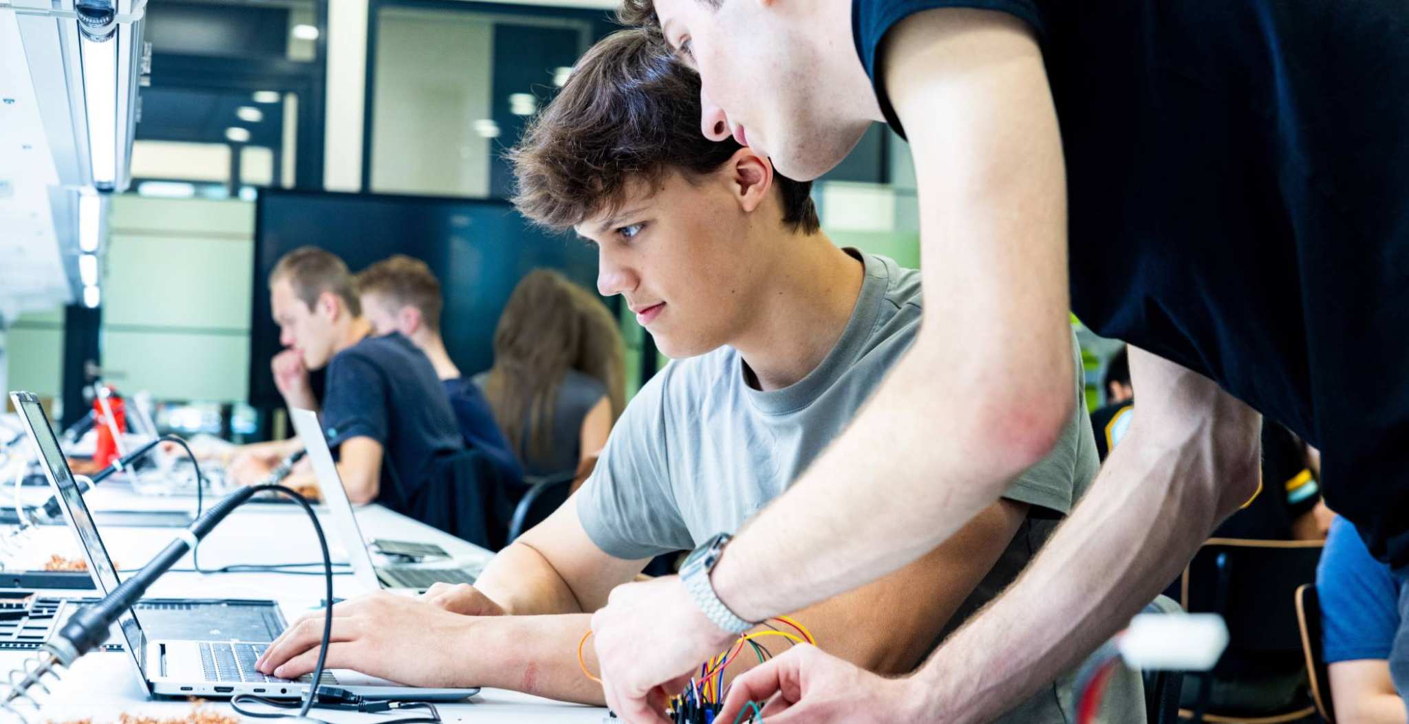 Studenten embedded systems engineering werken samen op de laptop in het lab.
