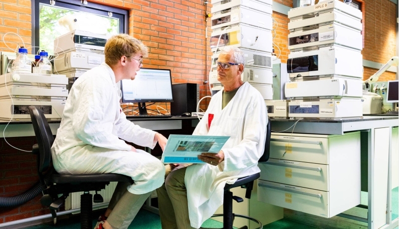 docent geeft uitleg aan student in chemie lab