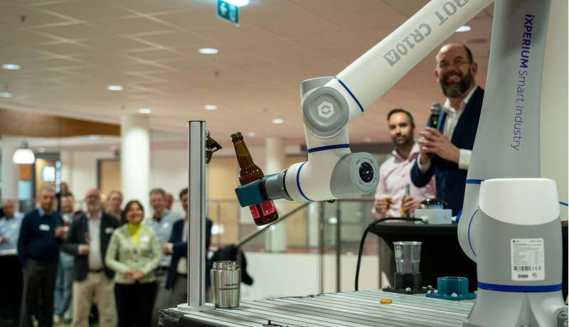 Het iXperium is geopend op 16 april. Een cobot pakt het door AI samengestelde biertje en schenkt een glas in.