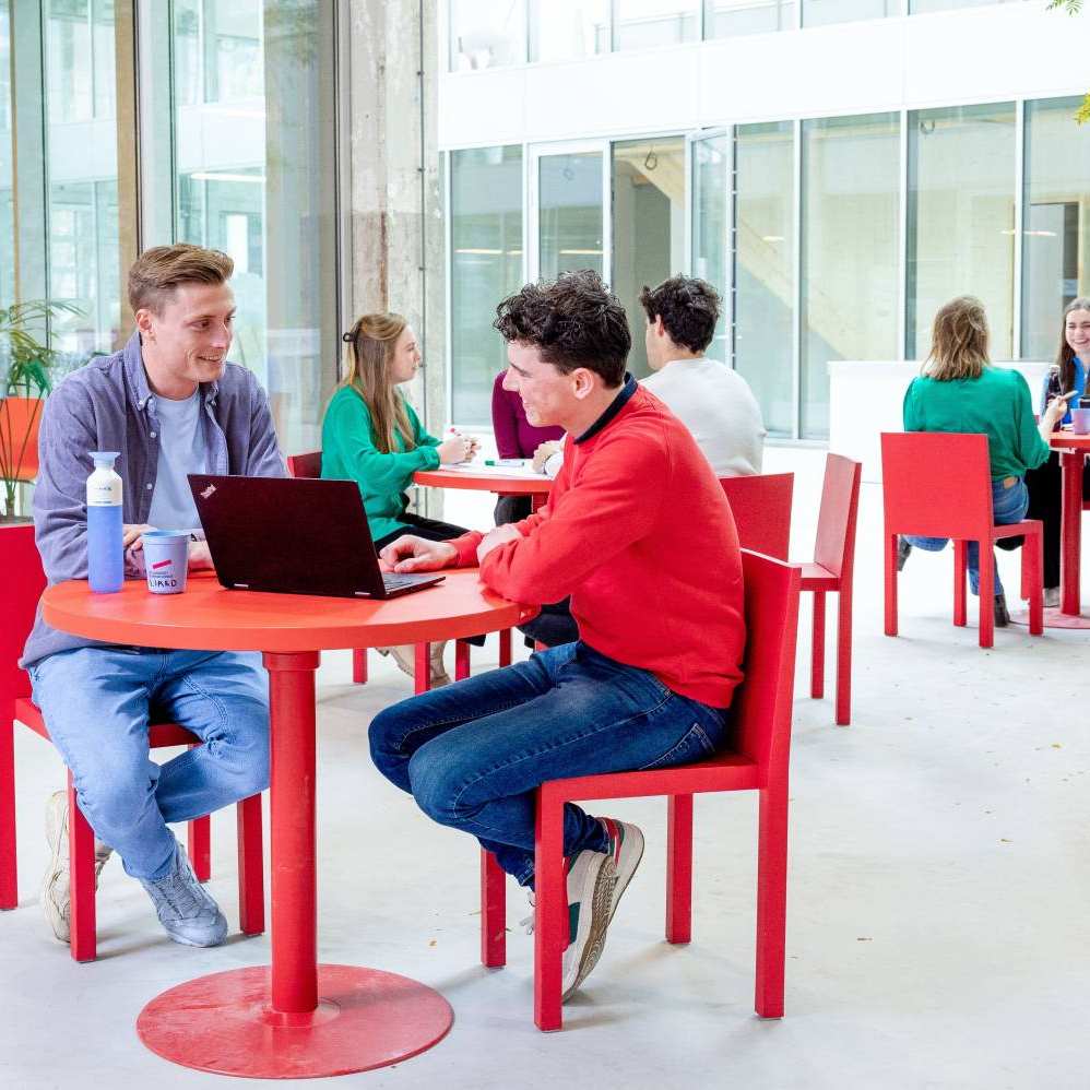 Locatieshot van IPKW met drie groepjes studenten aan tafel. Master Circulaire Economie 2024.