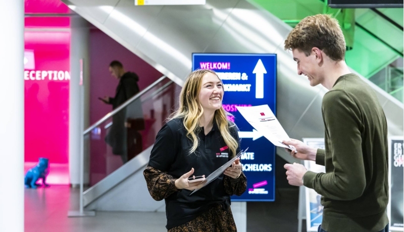 Een bezoeker praat met een deeltijdstudent tijdens de Open Avond op de HAN.