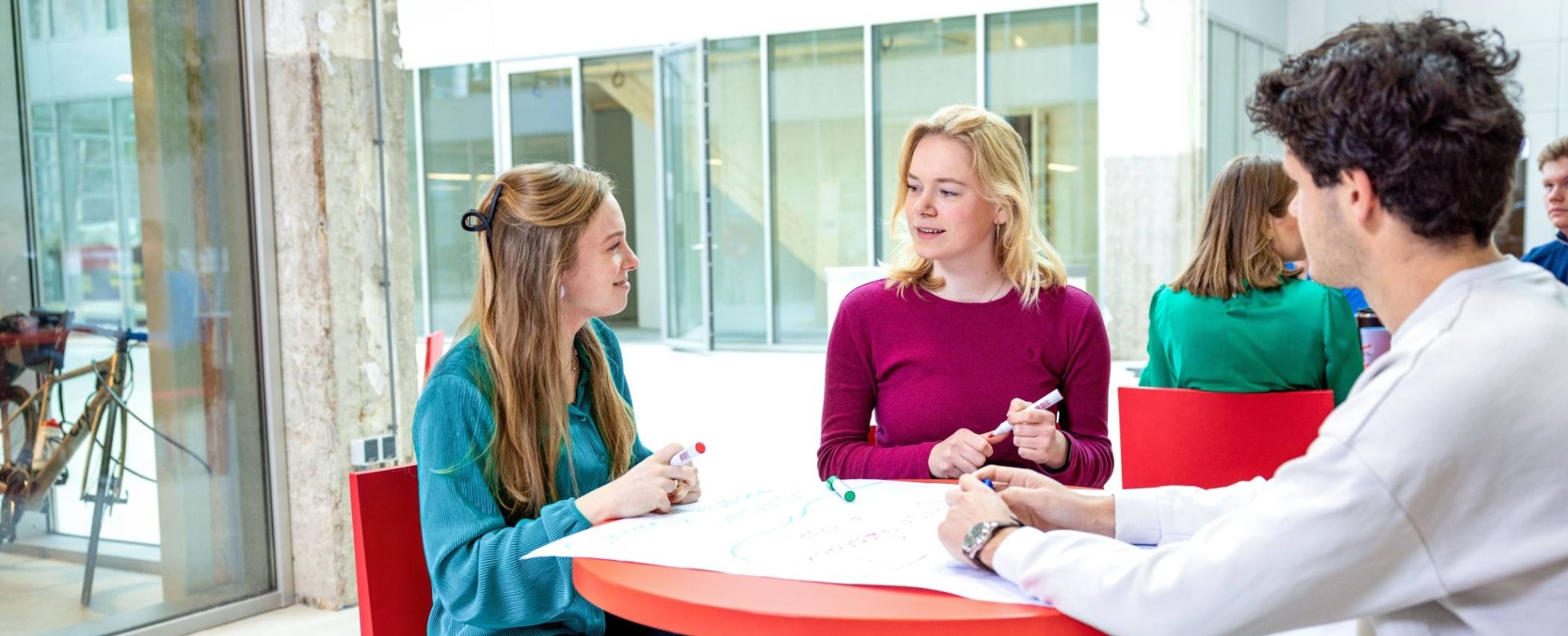 Lachende studenten aan tafel. Master Circulaire Economie 2024.