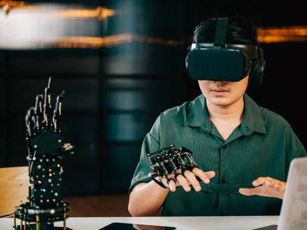 Afbeelding van een jongen met een VR-bril op die een robot hand bestudeert