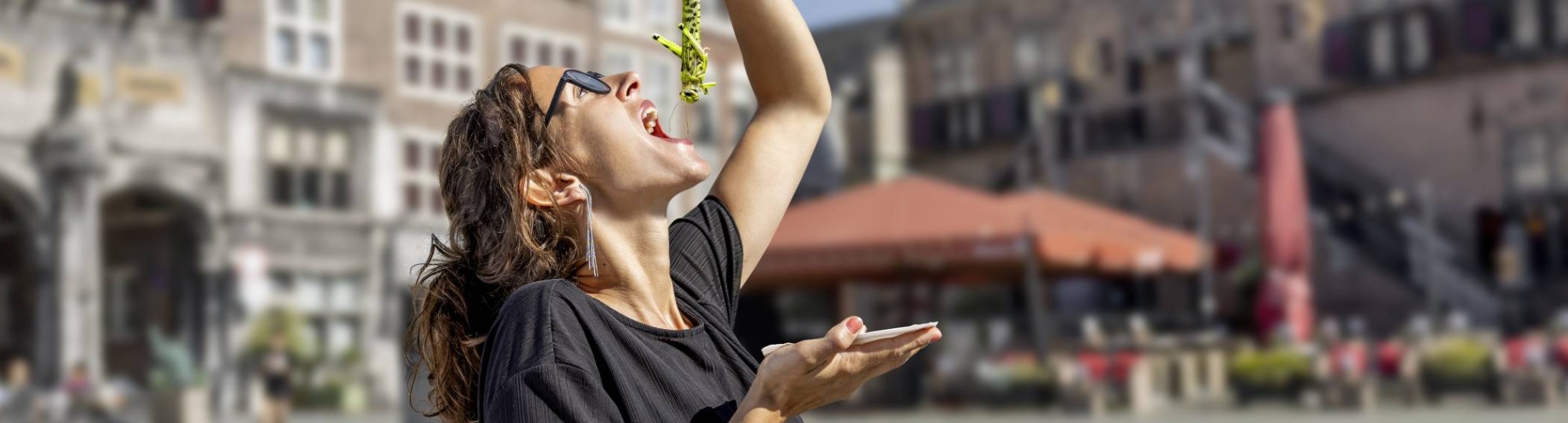 Een vrouw eet een krekel alsof het een haring is