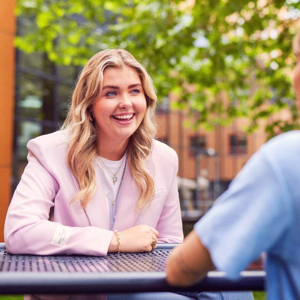 werving voltijd campagne, twee studentes in gesprek aan een picnictafel in de binnentuin.