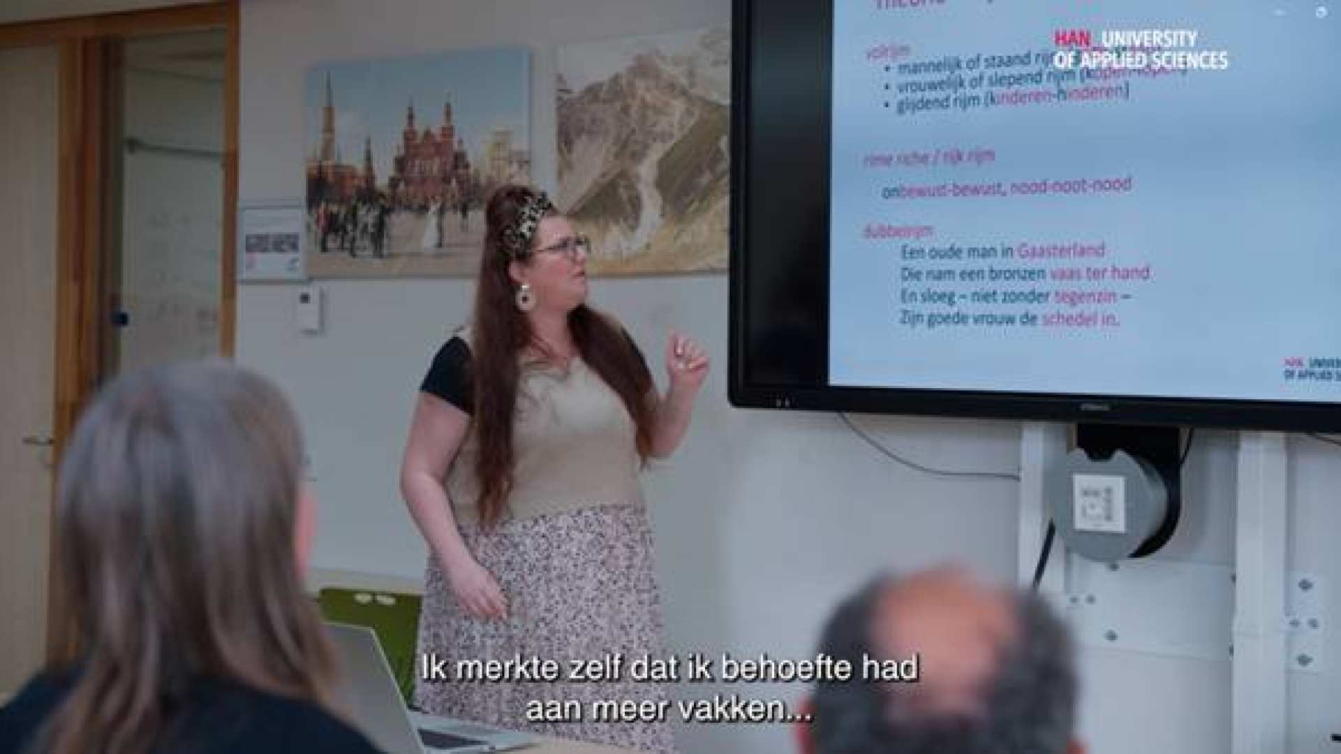 Student Leraar Nederlands staat voor de klas en wijst naar het bord
