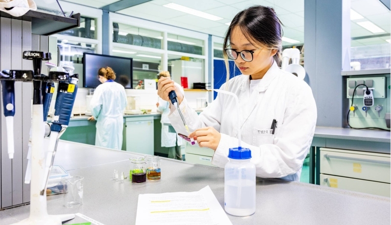 student aan de slag met een pipet in het chemielab