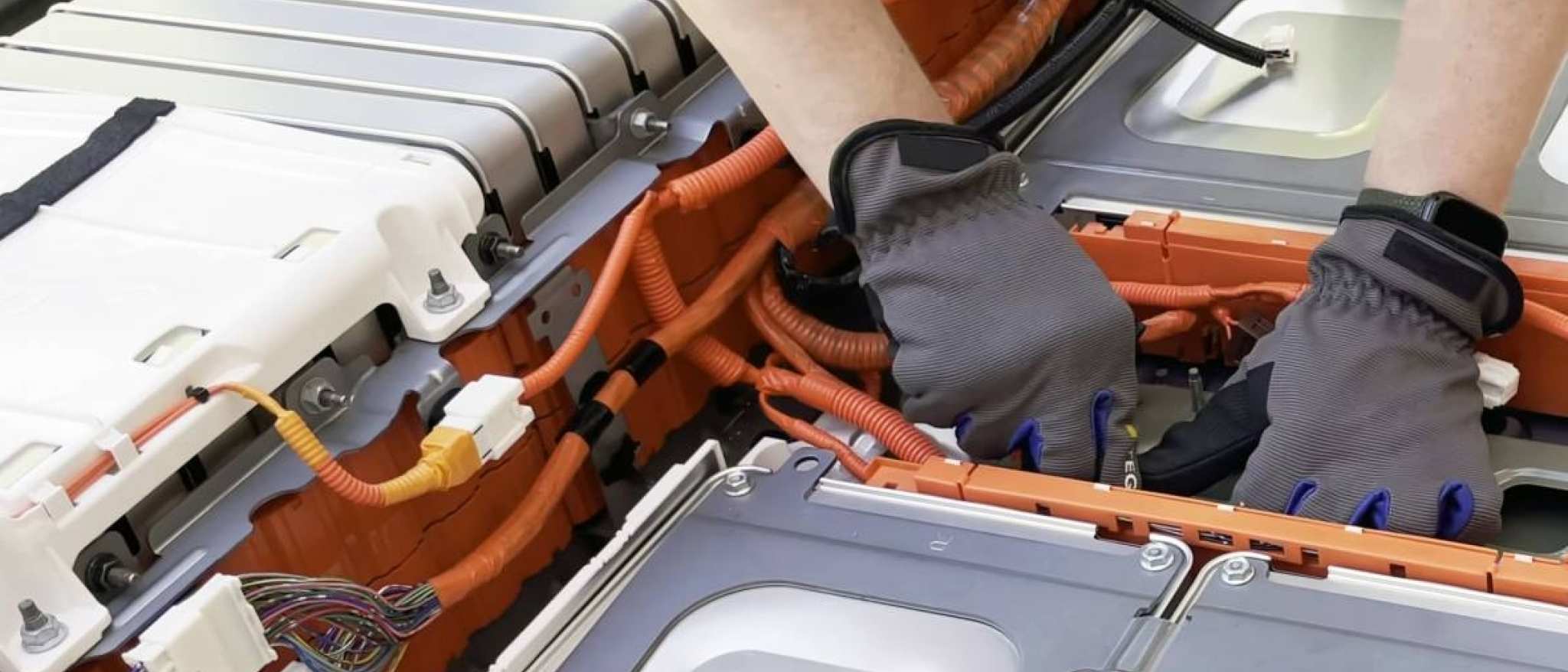 Monteur met blauwe handschoen knutselt aan een grote batterij. Seece - SEE- elektrotechniek, werktuigbouwkunde