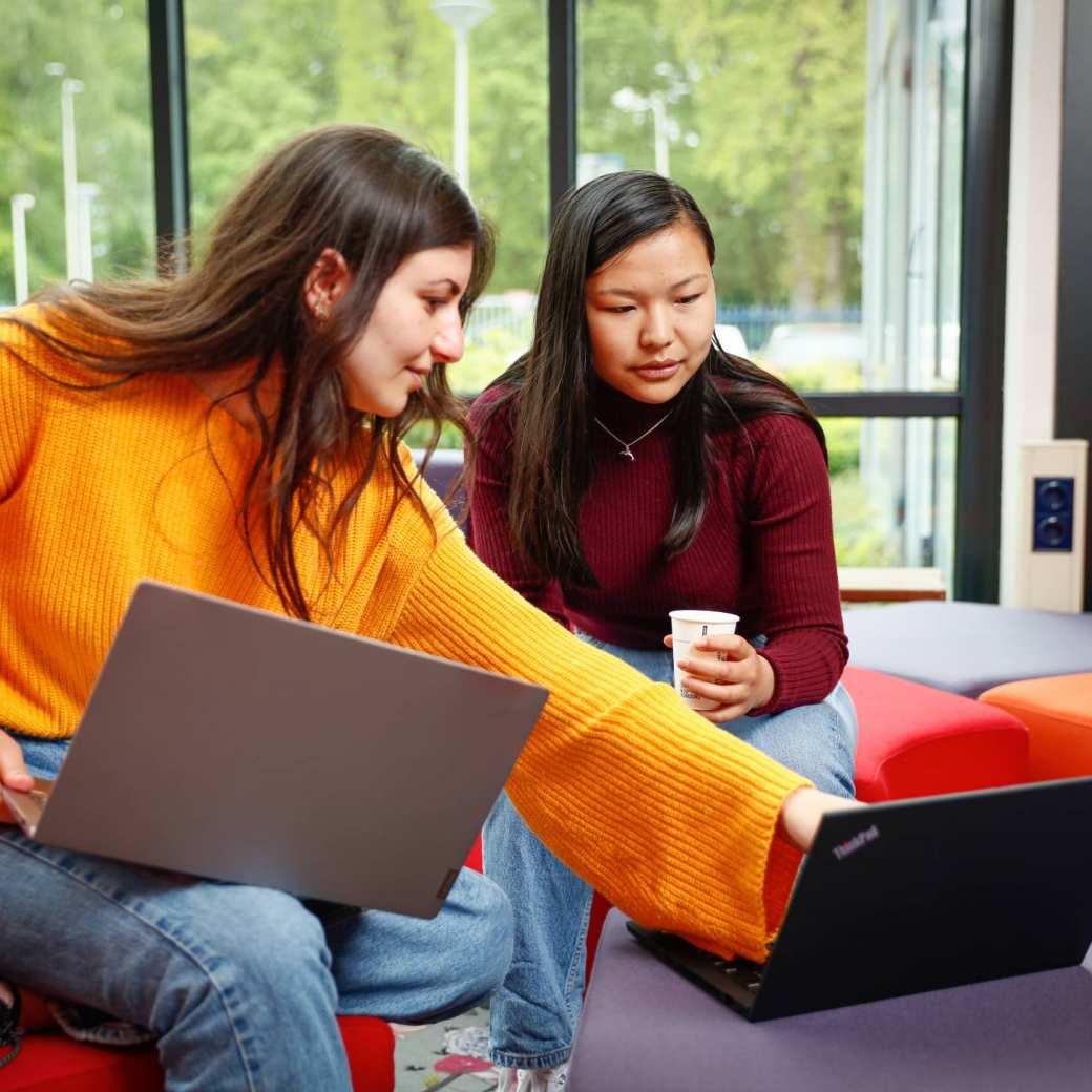 Twee studenten met laptop overleggen en wijst naar scherm