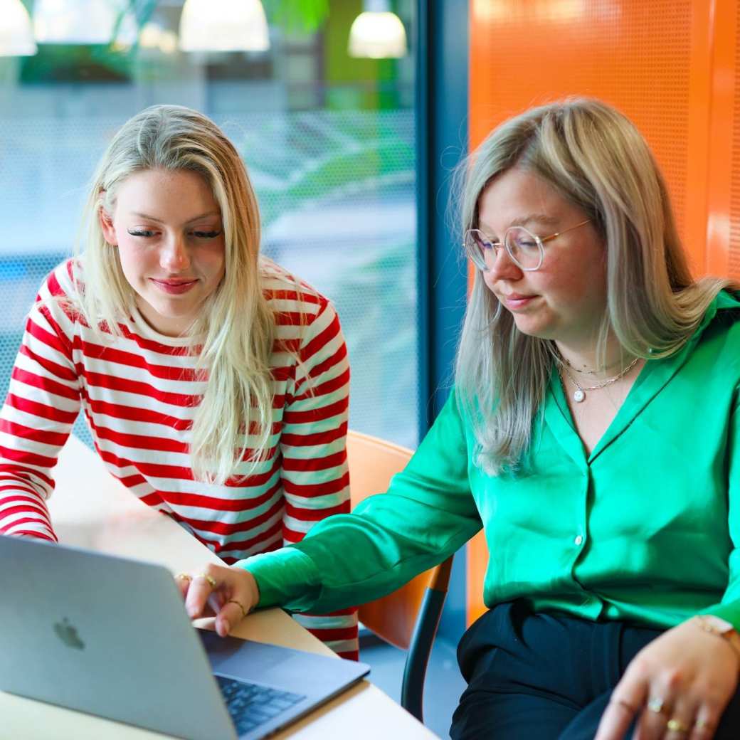 Twee studenten Human Resource Management werken samen achter de laptop