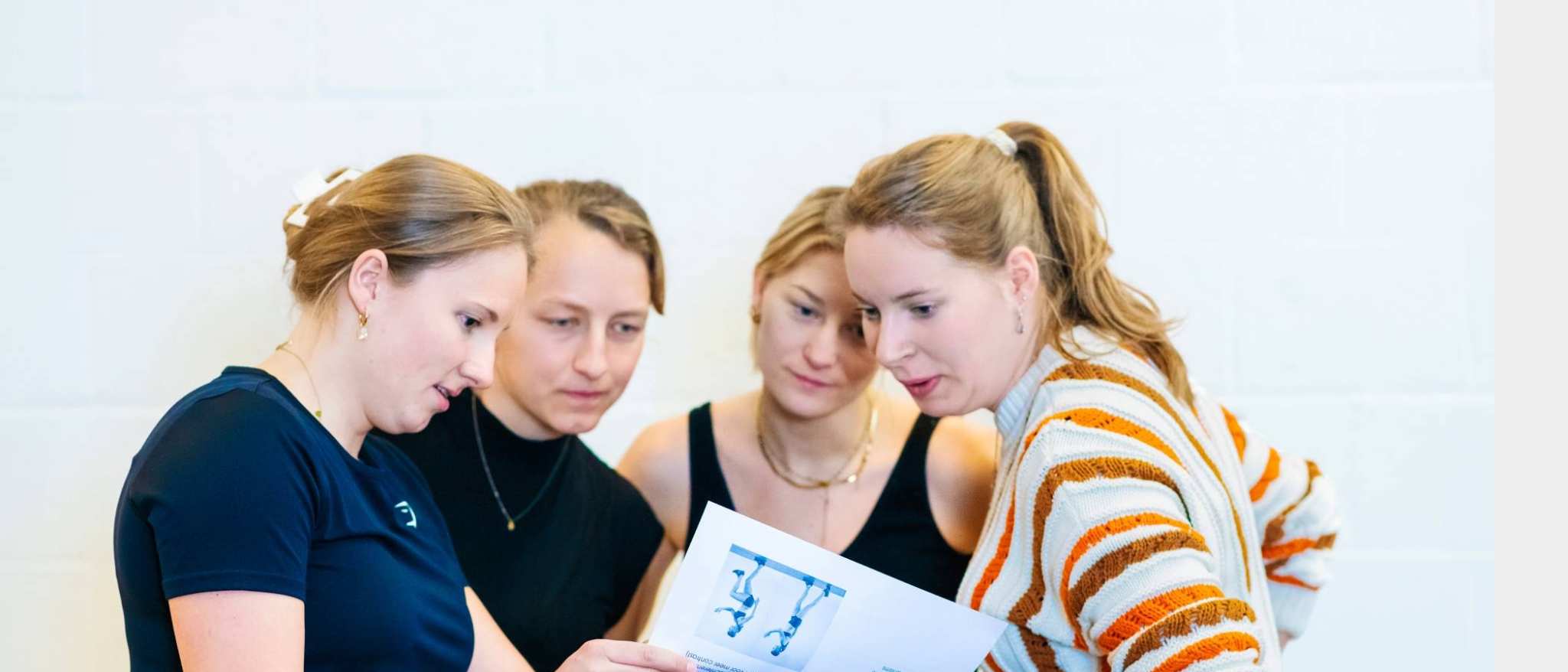 4 vrouwelijke studenten bekijken een oefening op papier.