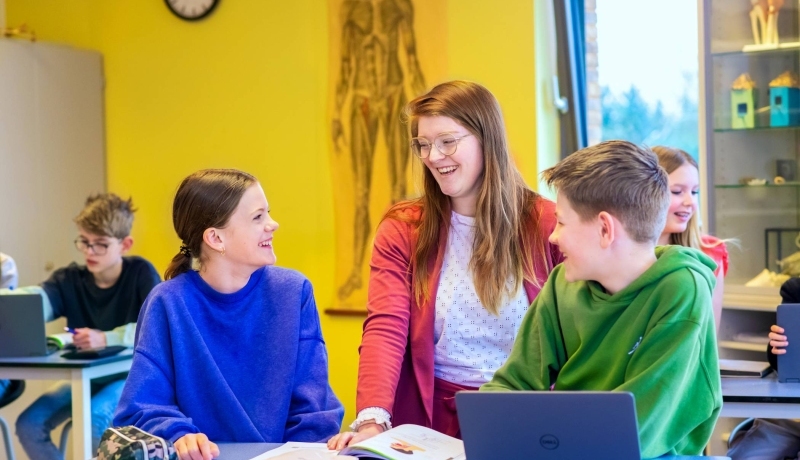 Fotoshoot op het Citadel 2024. De docente lacht met 2 scholieren in de klas. 