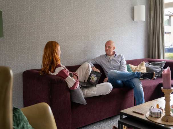 Vader en dochter zijn samen in gesprek op de bank.