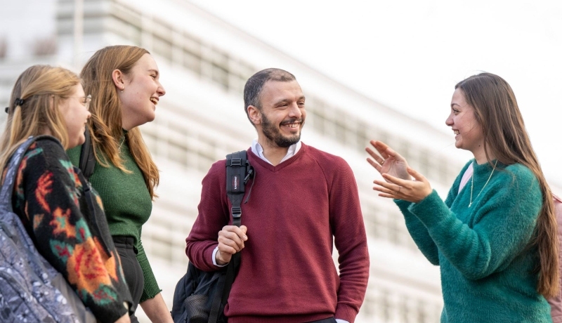 4 studenten praten buiten met elkaar.