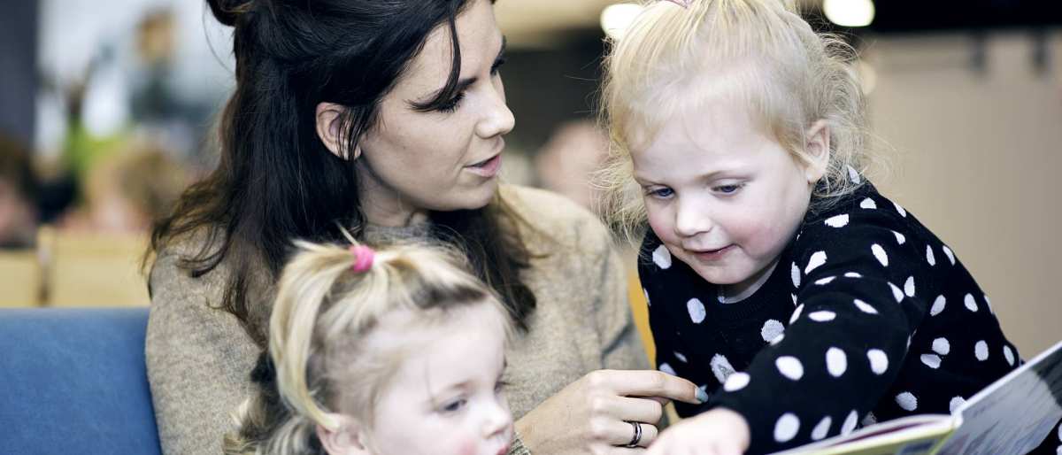 Kinderen lezen boek met docent