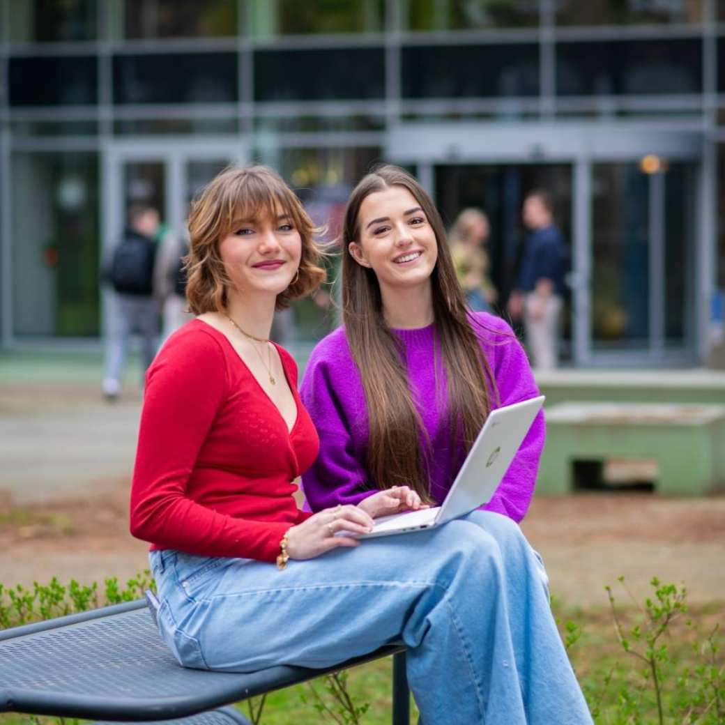 Studenten van Learning and Development in Organisations voltijd kijken lachend in de camera buiten voor Laan van Scheut 10 in Nijmegen.