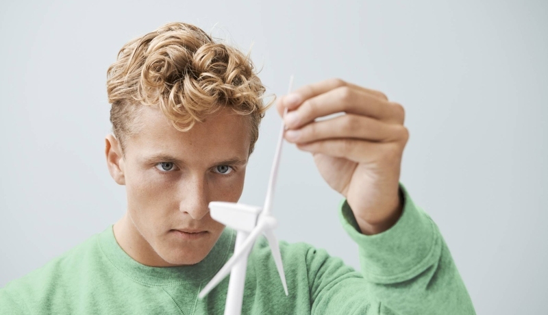 jongen met blonde krullen en een groene trui met model van een windmolen