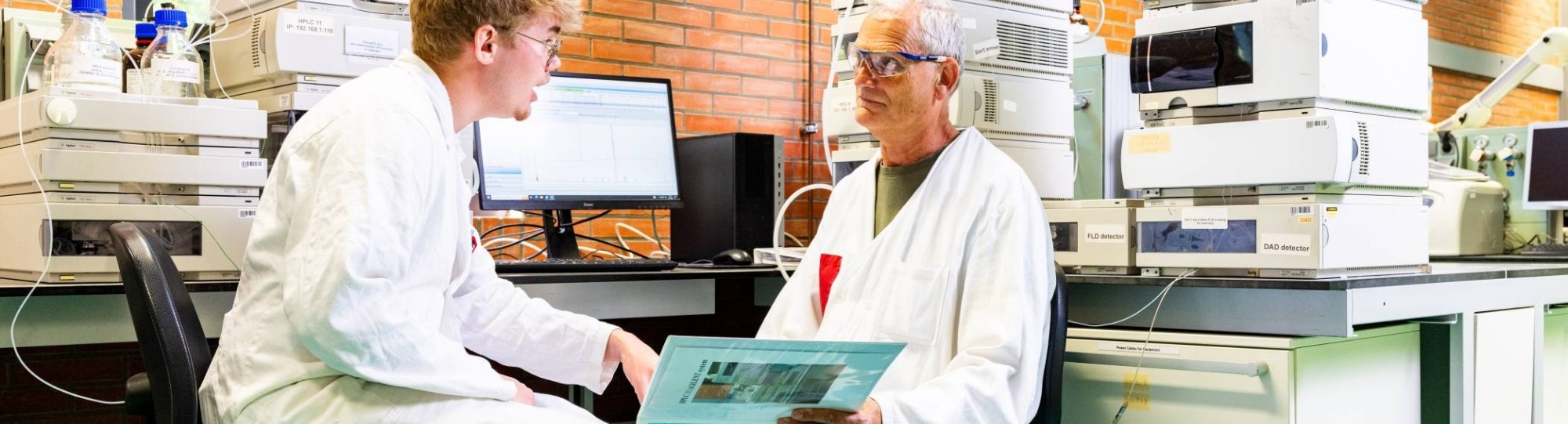 docent geeft uitleg aan student in chemie lab