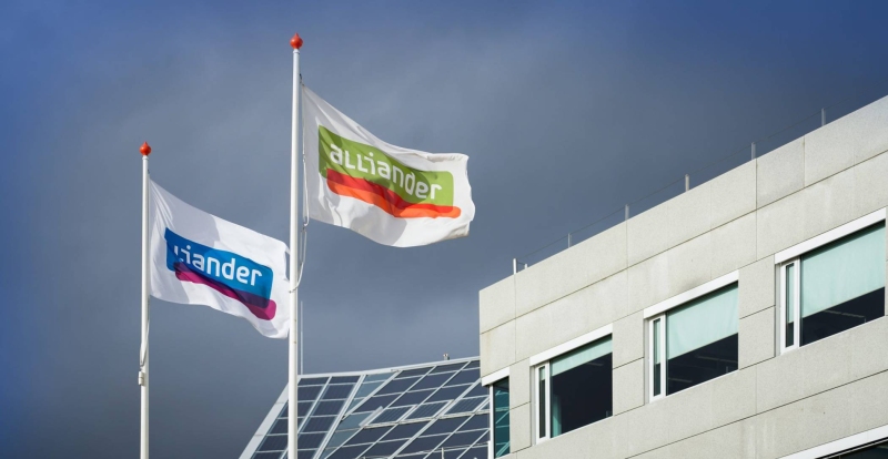 De vlag van Alliander wappert voor een gebouw. Seece