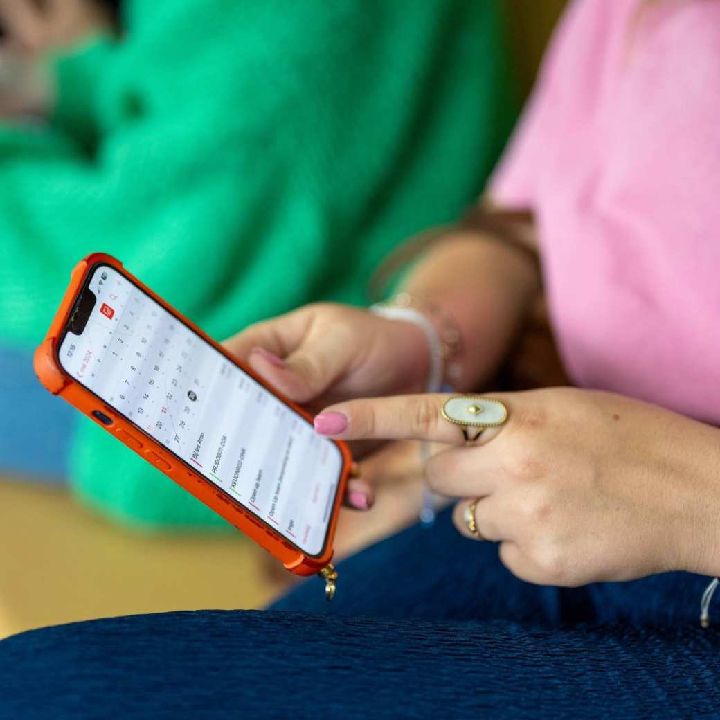 Student houdt haar telefoon vast en wijst er met haar vinger iets op aan. 