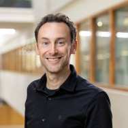 Portretfoto Frank Willems, zwart t-shirt met daarover zwarte blouse dragend