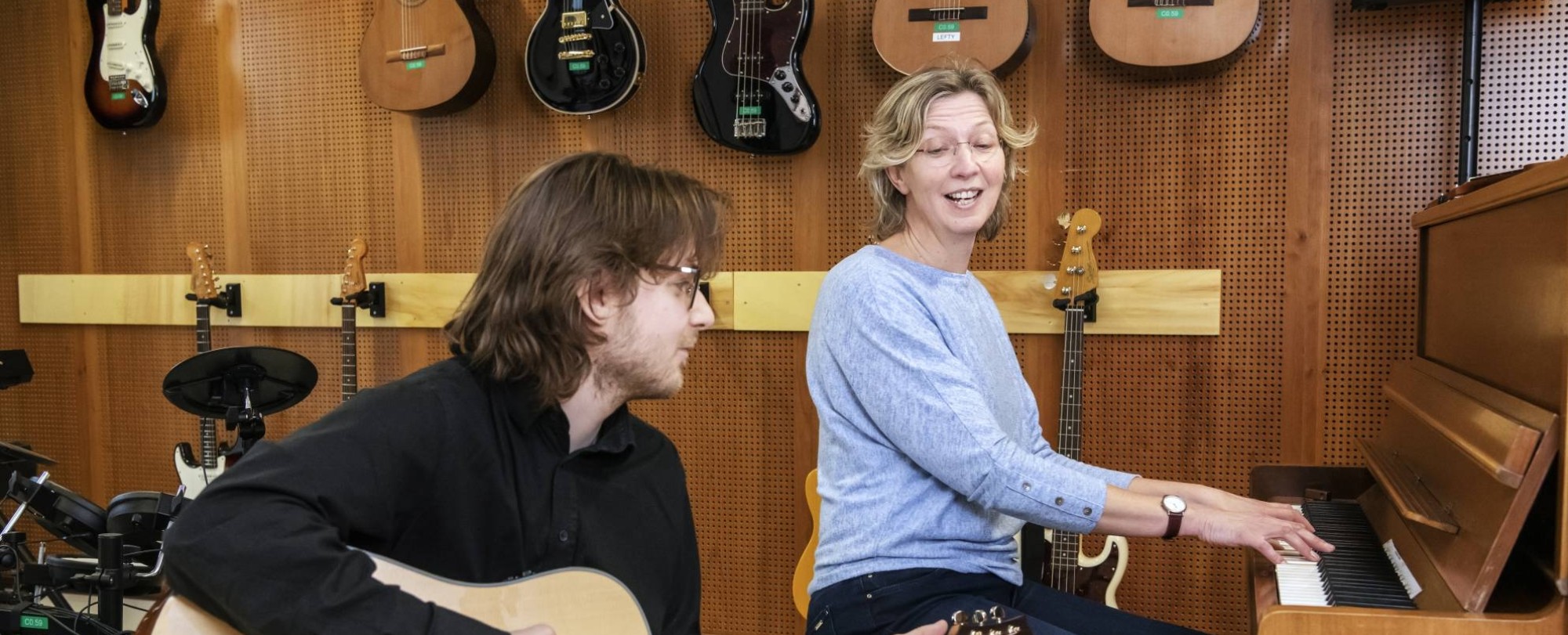 een docent en twee studenten van de han master vaktherapie muziektherapie maken samen muziek op gitaar en piano