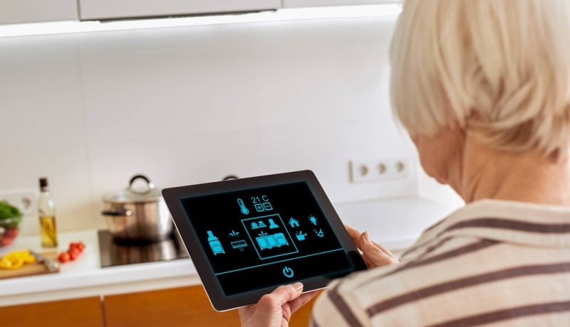 Oudere dame werkt met een tablet om op een innovatieve manier haar woning te bedienen.