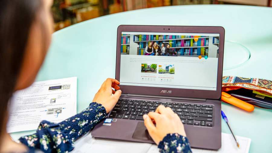 Student achter laptop met book your room app