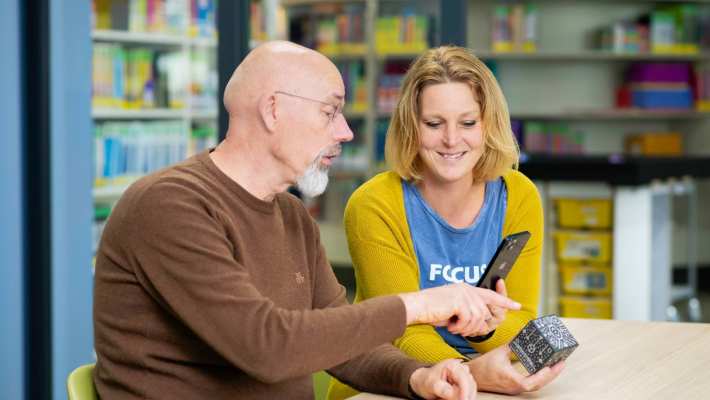 2 deeltijdstudenten overleggen in de bibliotheek.