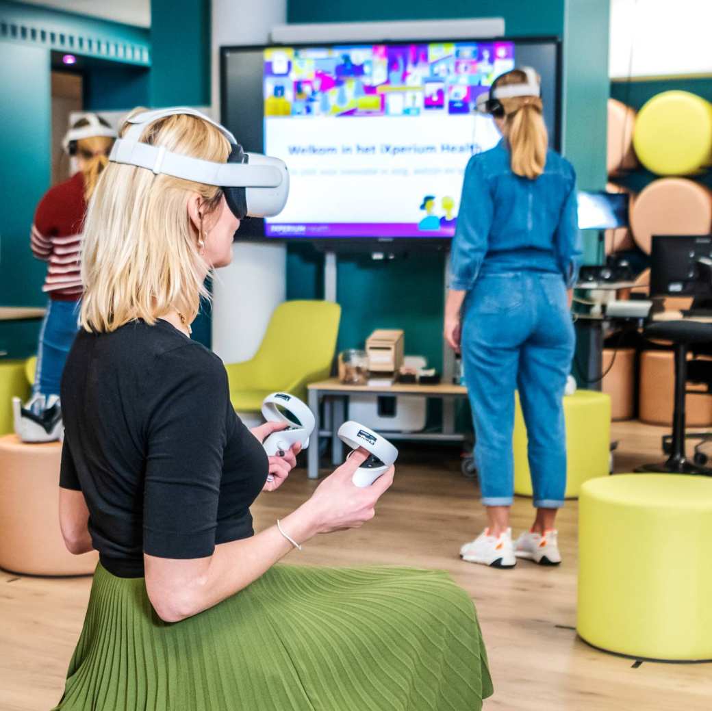 Foto van iXperium Health, waar 2 studenten en een docent een VR-bril op hebben.