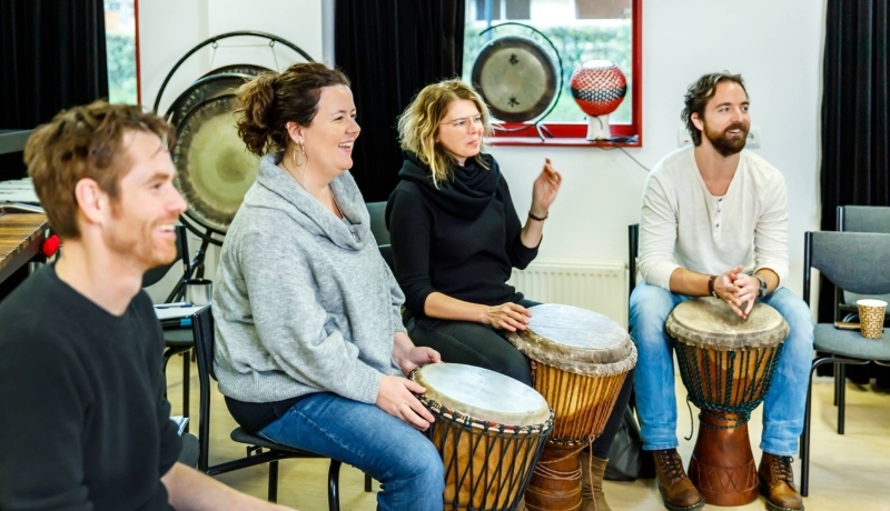 Studenten van de Master Vaktherapie - richting Muziektherapie - slaan op trommels.