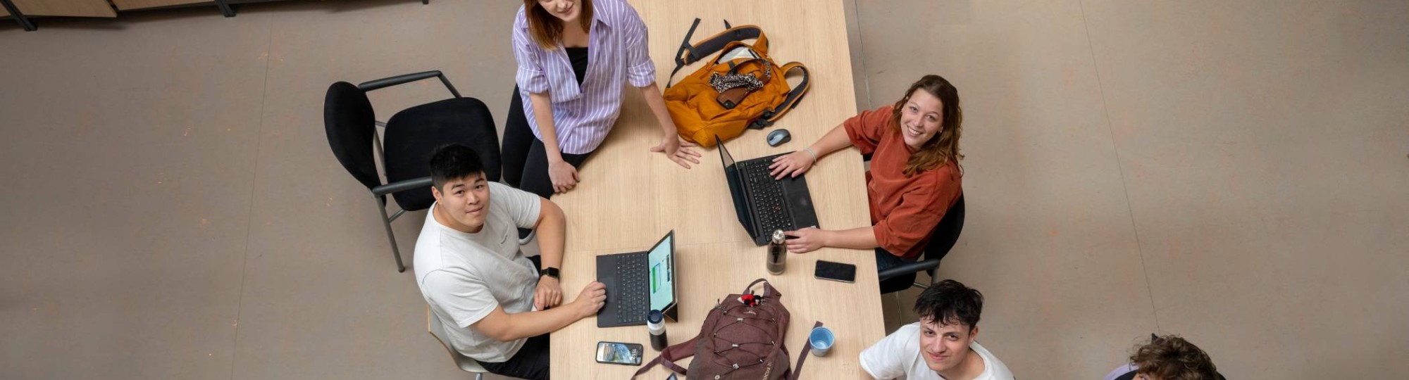 studenten in collegezaal laptop en boeken nodig
