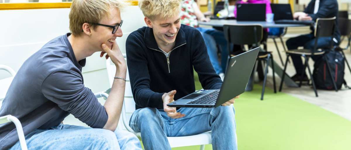 Twee hbo-ict studenten kijken samen lachend naar hun laptop