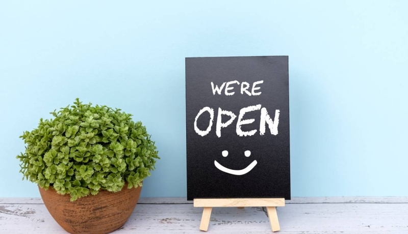 Een bord tegen een blauwe achtergrond met de tekst 'we're open' erop.