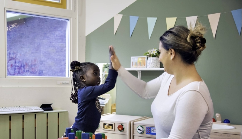 Docente geeft een high five aan een meisje.