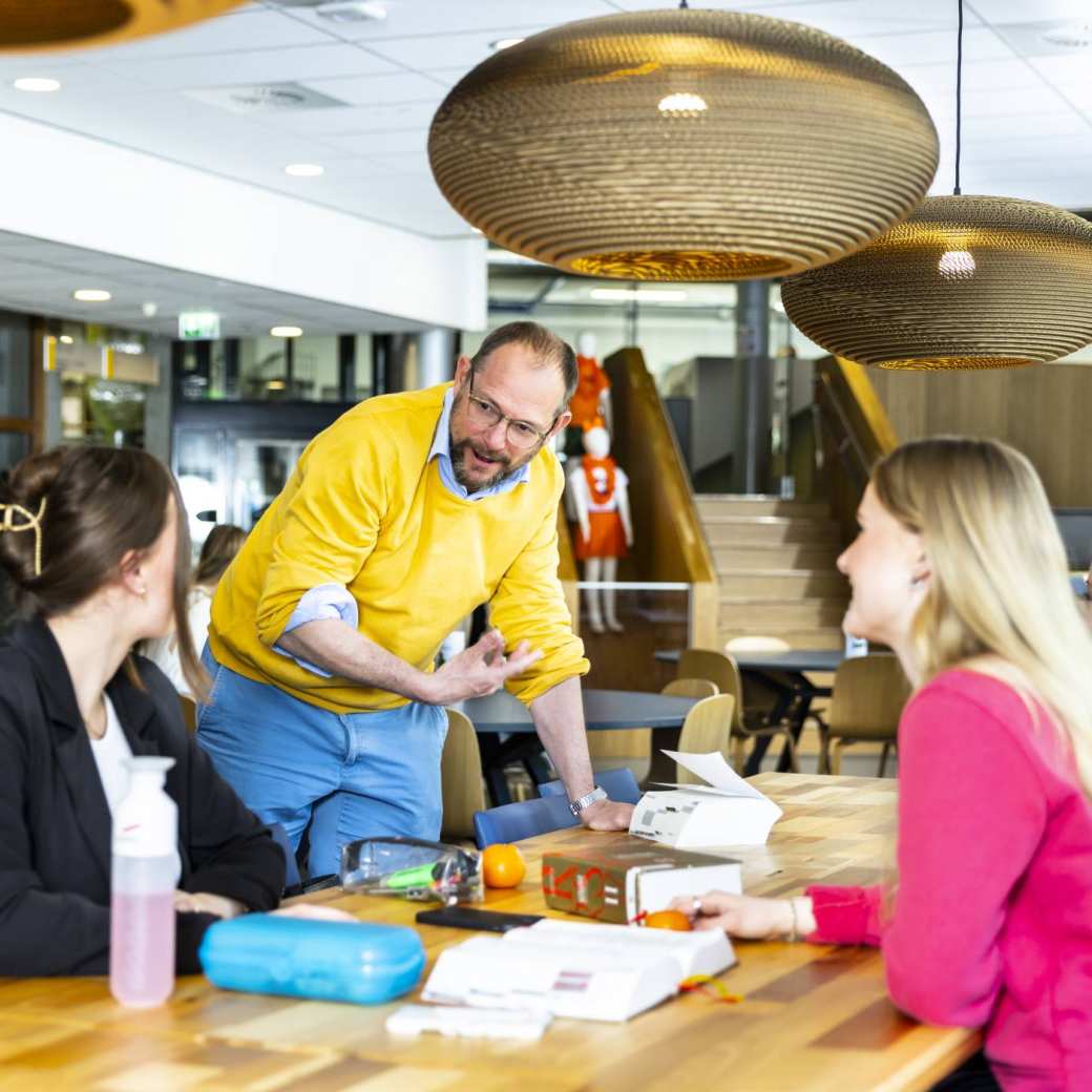 Studenten aan tafel met een docent.