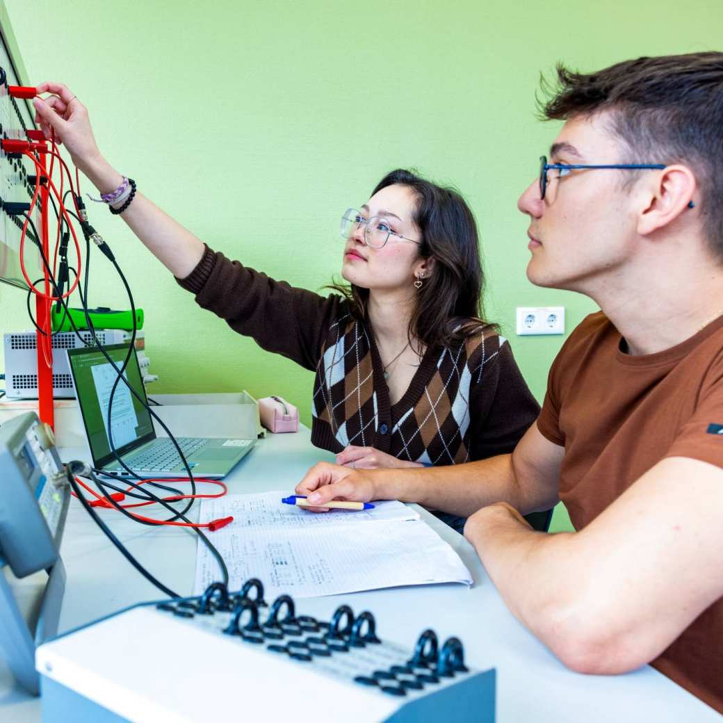 Twee studenten elektrotechniek werken samen tijdens een practicumsituatie.