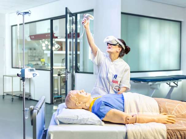 Verpleegkundige oefent met VR bril aan een ziekenhuisbed met dummy.