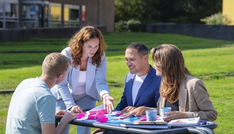 deelnemers master Business Sales samenwerken aan poster met post-its buiten op Ruitenberglaan 31 Arnhem.  