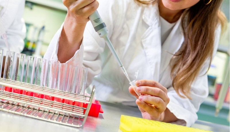 Student in het lab met reageerbuisjes en een pipet
