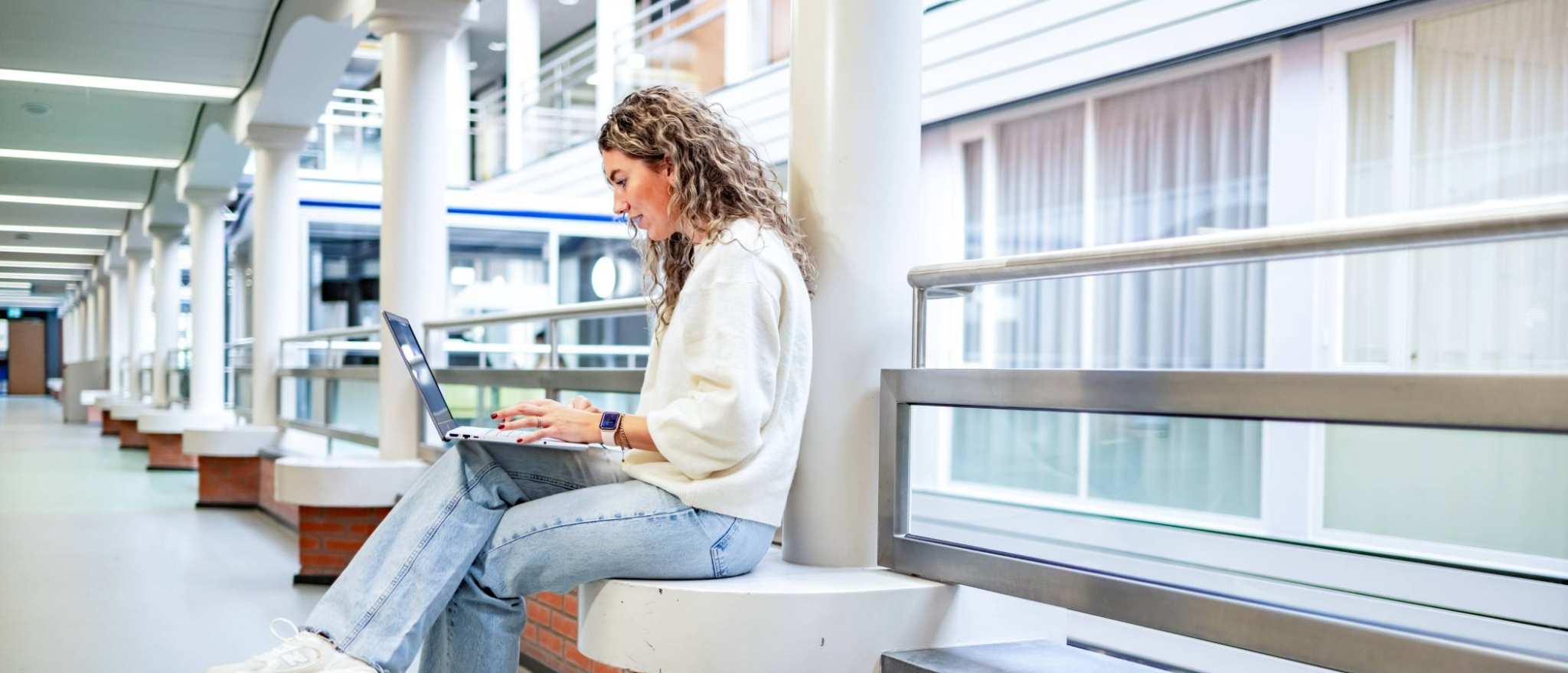 Student van de bachelor Commerciële Economie deeltijd, duaal in gang met laptop.