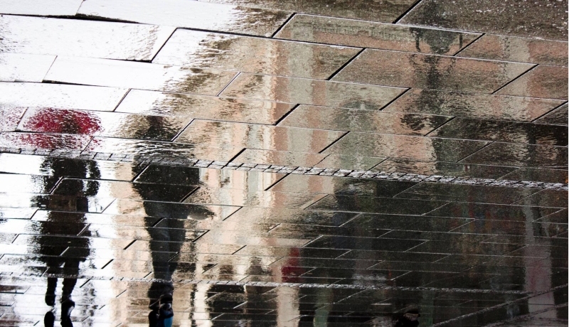 Mensen op straat in regen spiegelbeeld. Associate lectoraat Business Ethics lector Kim Meijer.