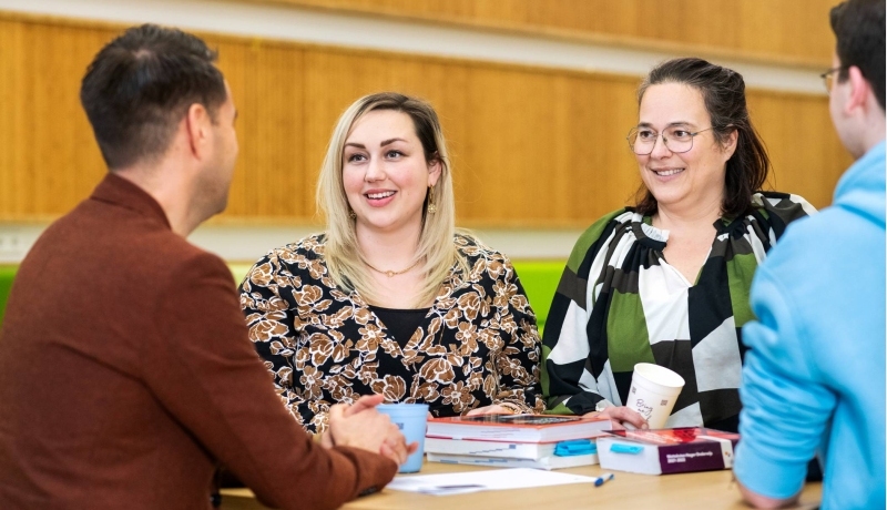 Twee vrouwen lachen tijdens een gesprek.